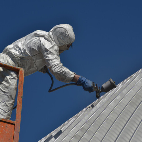 a worker applying a metal roof coating