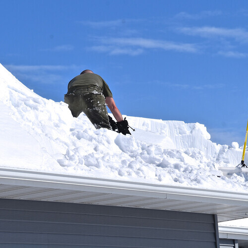 worker removing snow from a rooftop