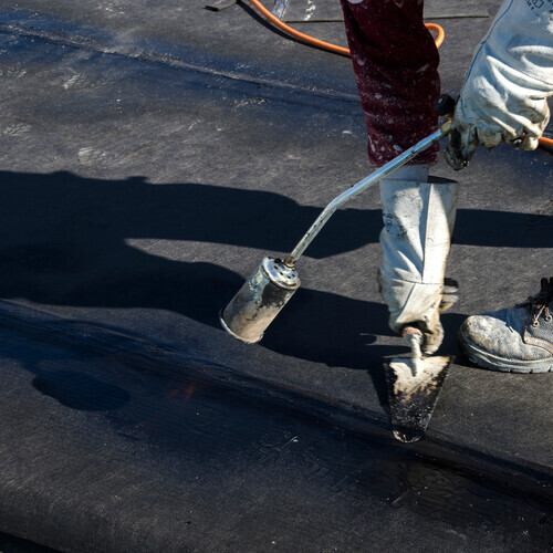 a worker applying a rubber roof coating